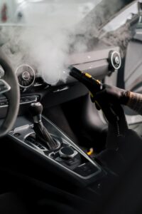Professional auto detailer in Morris County using steam cleaning equipment inside vehicle cabin